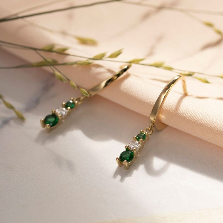 Yellow gold dangling earring with green and white zircons