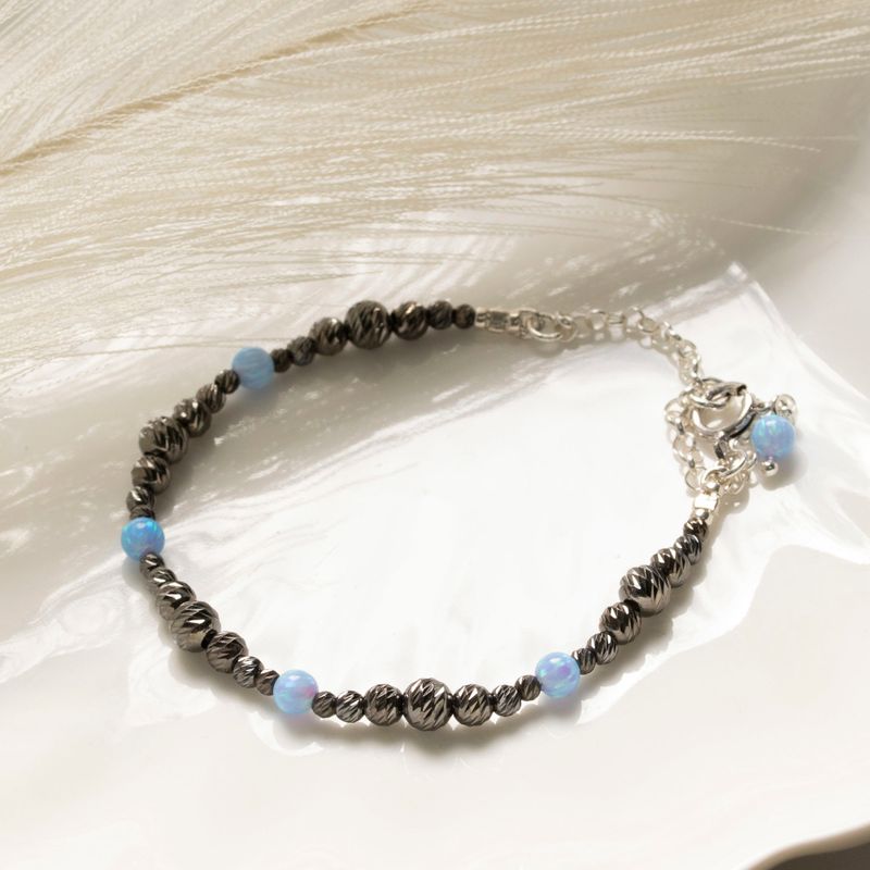Silver bracelet with rough black beads with blue opal beads and clasp