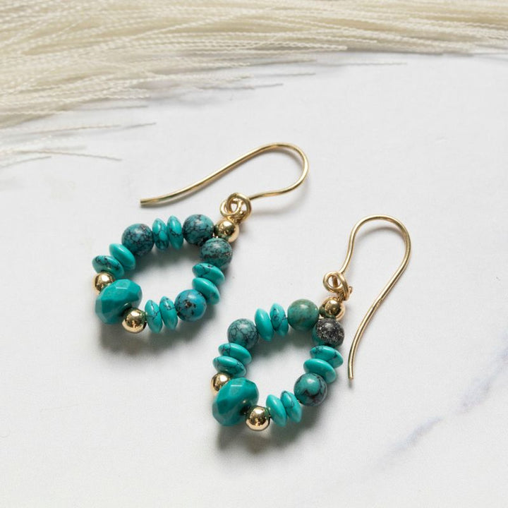 Yellow gold dangling earrings with turquoise and gold beads oval shape