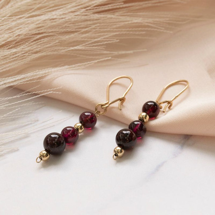Yellow gold dangling earrings with gold and garnet beads