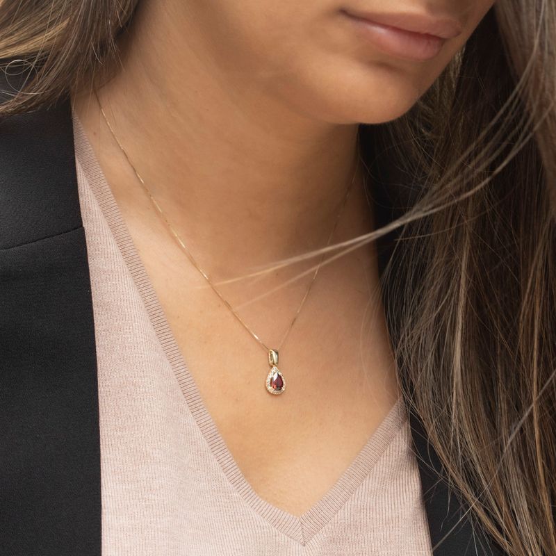 yellow gold drop necklace with white zircons and a garnet stone in the center