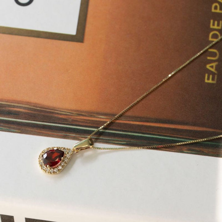 yellow gold drop necklace with white zircons and a garnet stone in the center