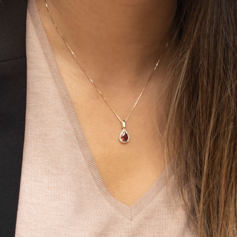 yellow gold drop necklace with white zircons and a garnet stone in the center