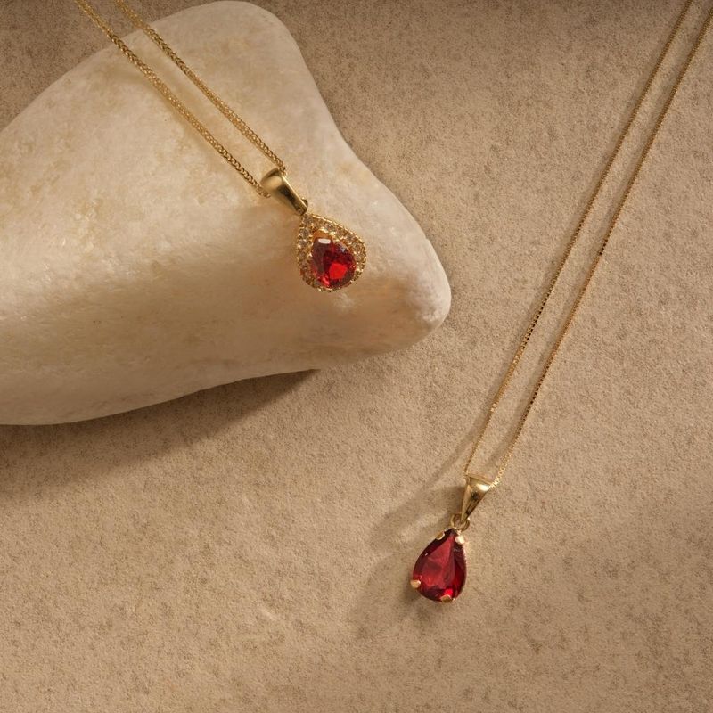 yellow gold drop necklace with white zircons and a garnet stone in the center