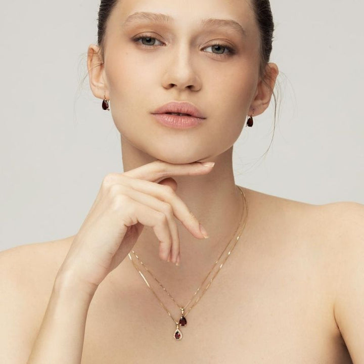 yellow gold drop necklace with white zircons and a garnet stone in the center