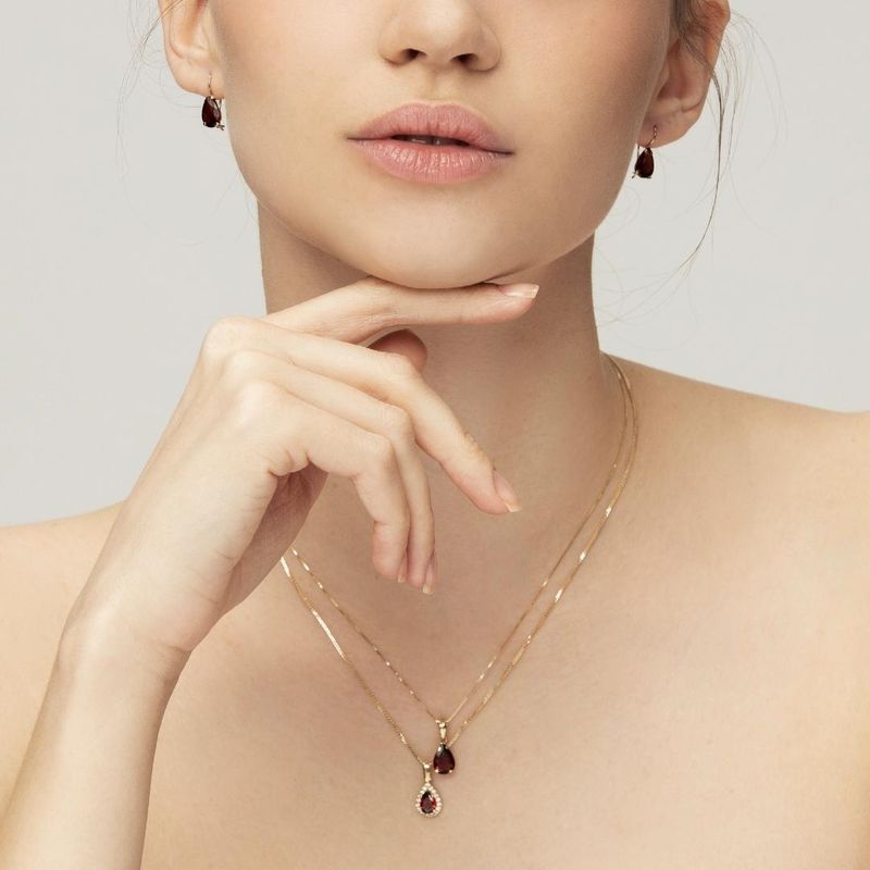 yellow gold drop necklace with white zircons and a garnet stone in the center