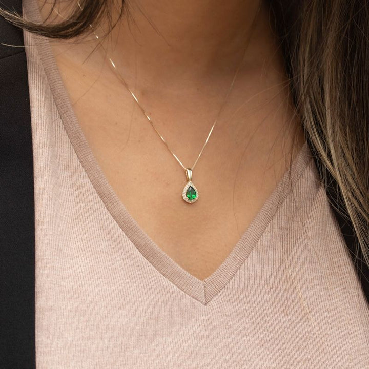 Yellow gold drop necklace with white zircons and a green zircon in the center