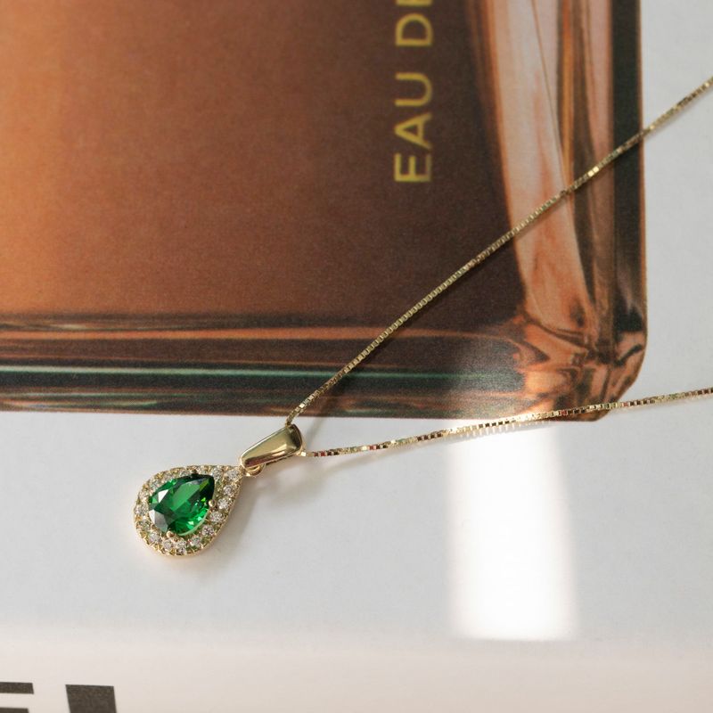 Yellow gold drop necklace with white zircons and a green zircon in the center