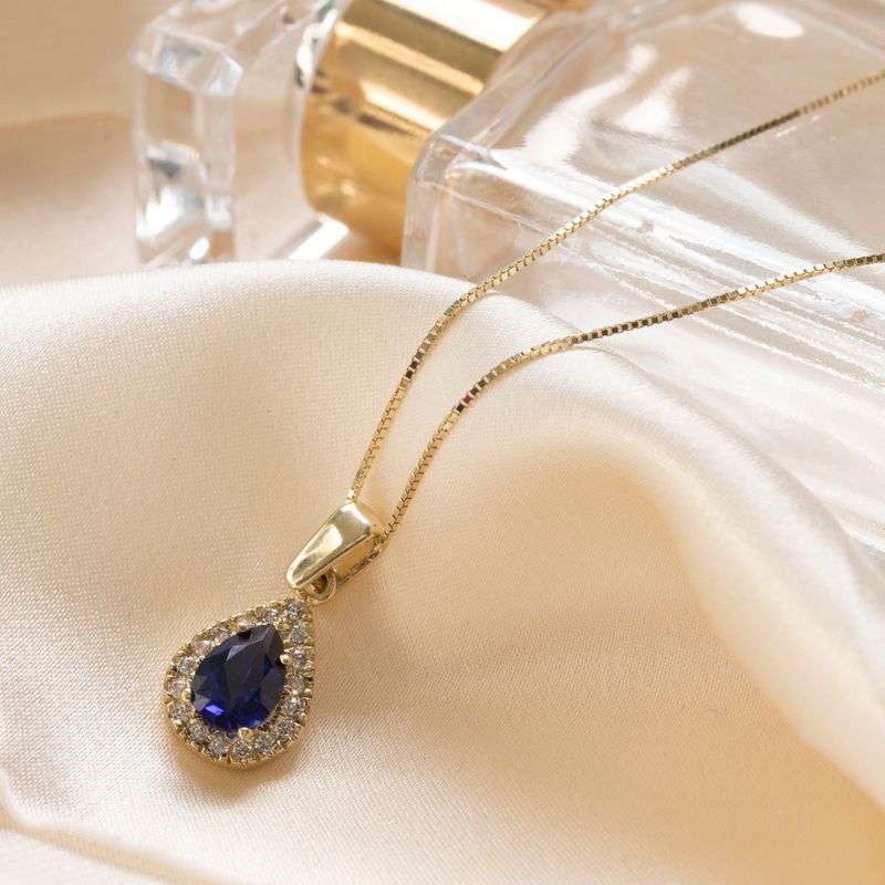 Yellow gold drop necklace with white zircons and a blue zircon in the center
