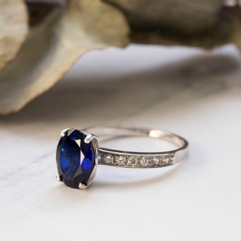 White gold ring with white zircons and a prominent oval blue stone