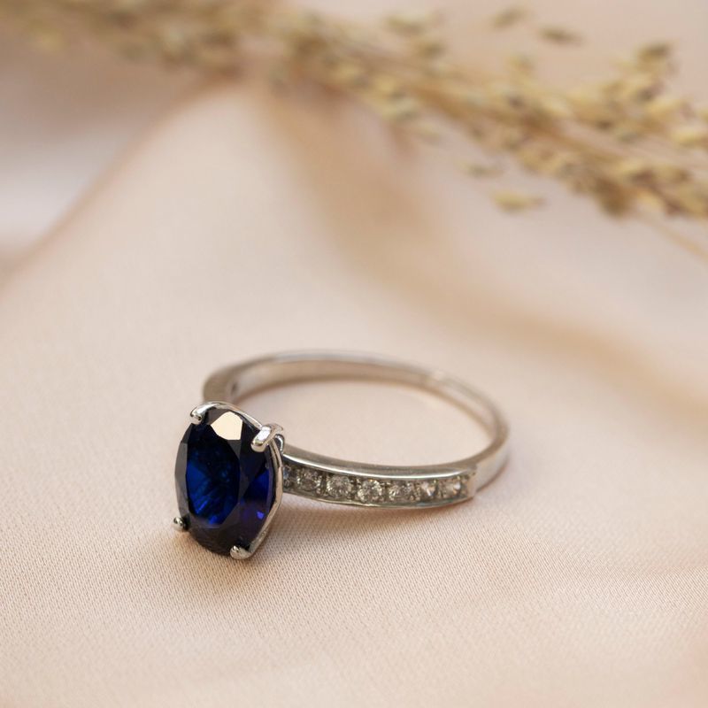 White gold ring with white zircons and a prominent oval blue stone