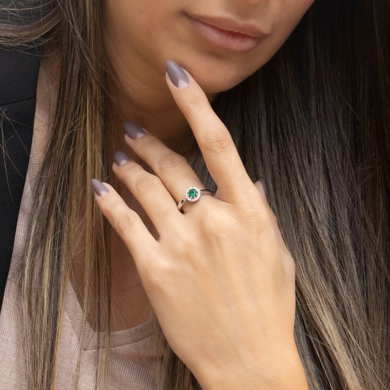 round yellow gold ring with white zircons and a green zircon in the center