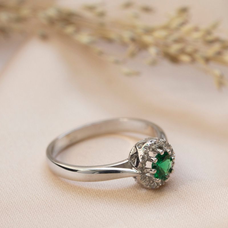 round yellow gold ring with white zircons and a green zircon in the center