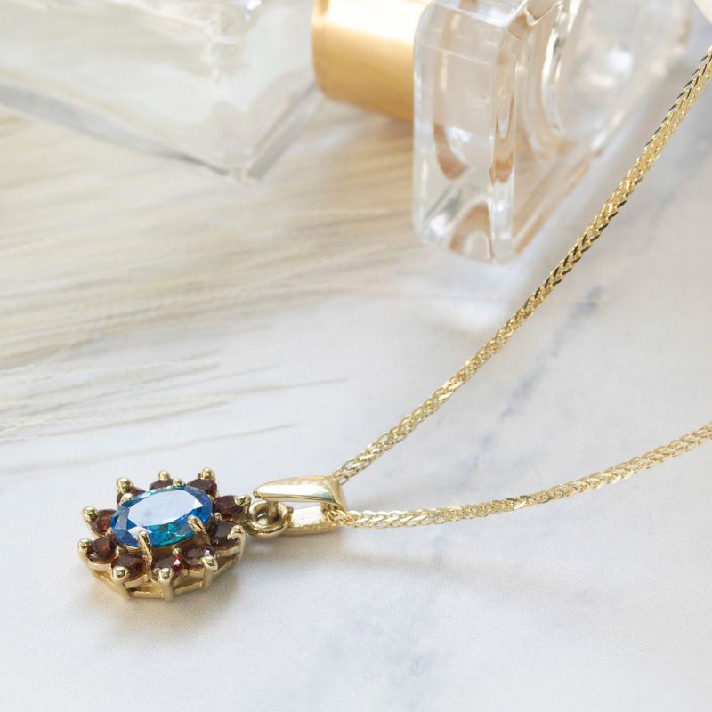 Lucia pendant yellow gold with garnet stones and blue zircon in the middle