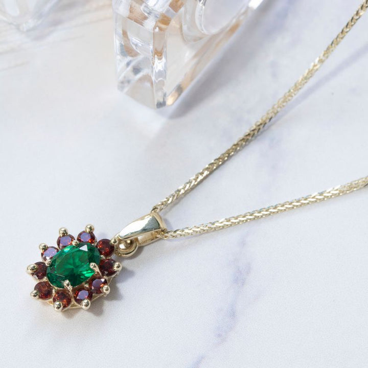Lucia pendant yellow gold with garnet stones and green zircon in the middle