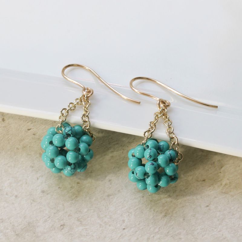 Yellow gold earrings with turquoise beads in a ball