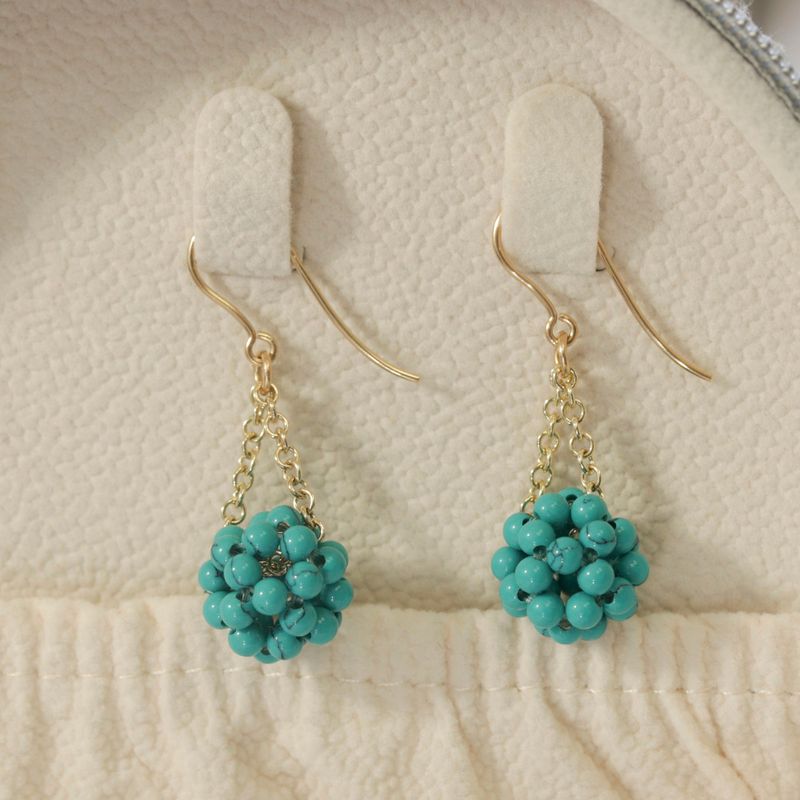 Yellow gold earrings with turquoise beads in a ball